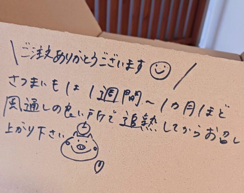 野菜が入った段ボールによしむら農園から手書きのメッセージが書かれている画像。「ご注文ありがとうございます。さつまいもは1週間~1か月ほど風通しの良い所で追熟してからお召し上がりください。」